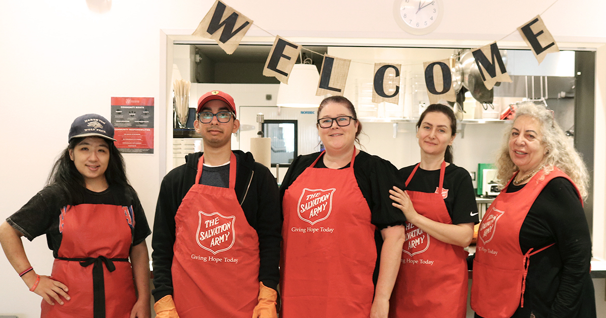 A group of five people in red Salvation Army aprons